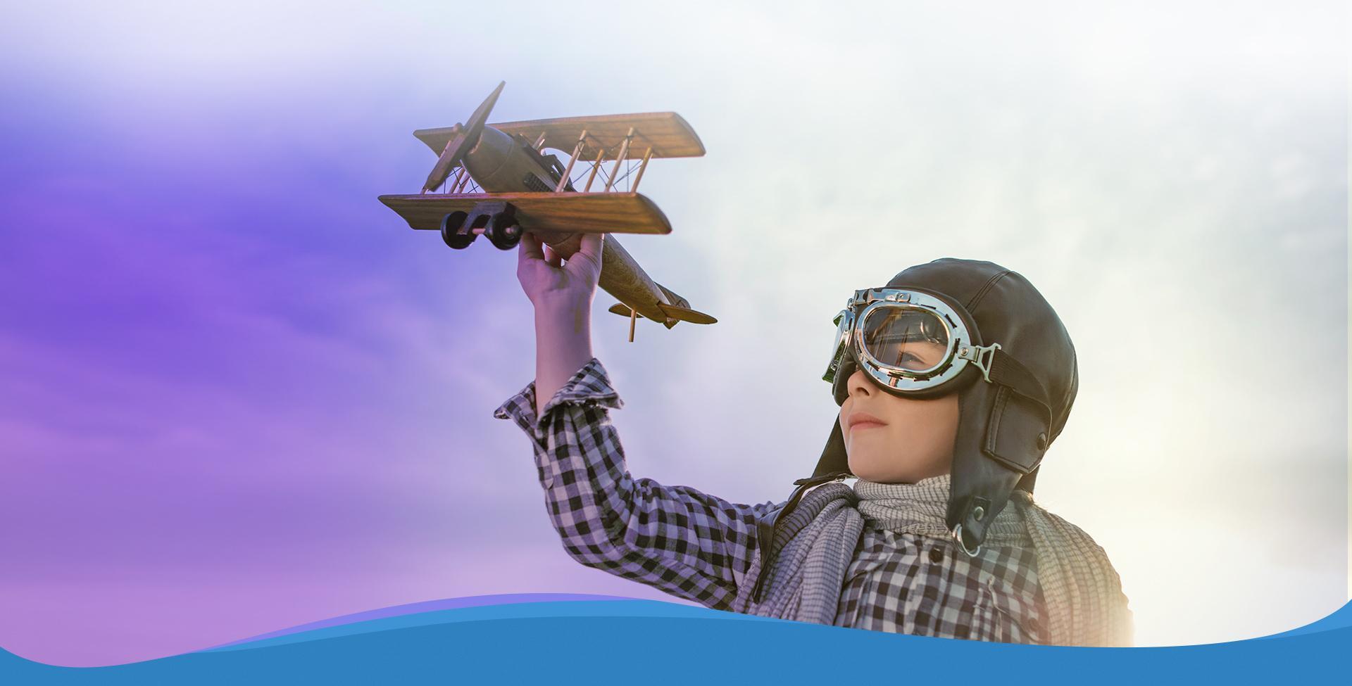 Slajd #3 - chłopiec w czapce lotnika z drewnianym samolotem